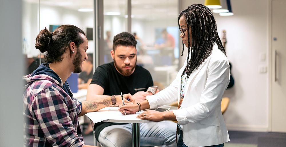 Four people standing around a table talking Four people standing around a table talking